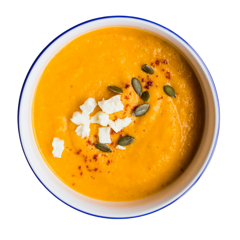 a bowl of sweet potato cream soup sprinkled with pumpkin seeds and feta